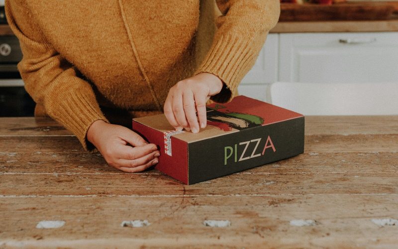 a person putting a pizza in a box on a table
